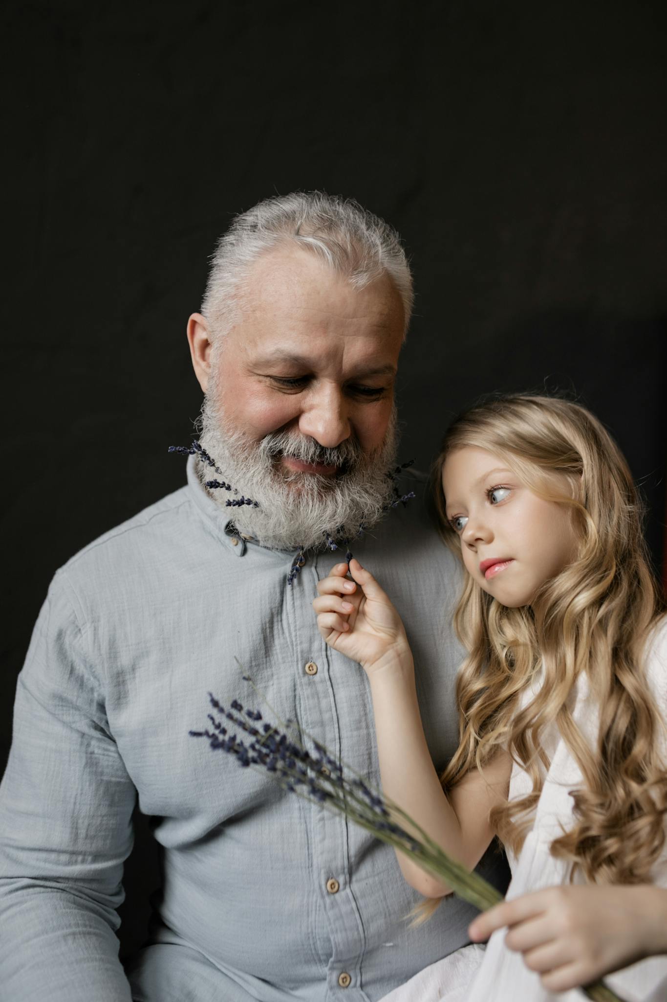 Charming scene of a granddaughter playing with her bearded grandfather, showcasing love and family bonds.
